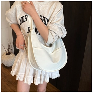 White crescent crossbody bag showing capacity and fit on a model in a casual outfit