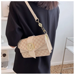 Détail du sac à bandoulière en toile beige avec motif M et boucle ronde dorée