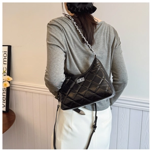 Détail du sac bandoulière en cuir noir matelassé avec chaîne argentée et fermoir rotatif