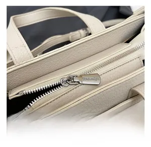 Detailed macro view of litchi leather handbag with silver zipper and metal twist lock