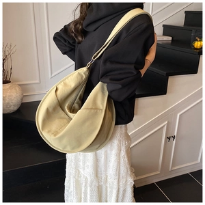 Spacious beige nylon hobo bag shown on shoulder in a minimalist indoor lifestyle setting