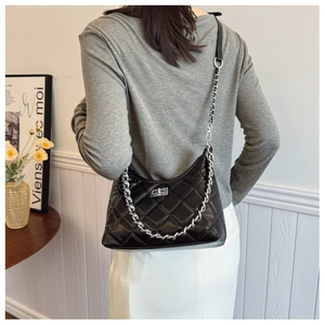 Détail du sac bandoulière en cuir matelassé noir avec chaîne argentée et fermoir