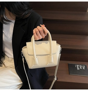 Detail of cream lychee texture leather handbag with silver hardware and adjustable strap
