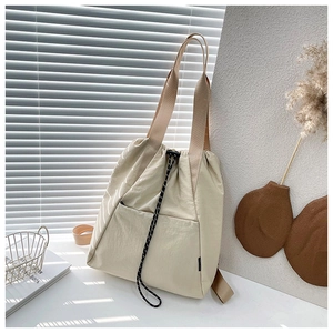 Detail view of cream nylon drawstring bucket bag on a minimalist styled tabletop