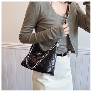 Détail du sac matelassé noir avec fermoir rotatif argenté et texture cuir brillant