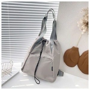 Detail of grey drawstring nylon backpack with woven rope and side utility pocket
