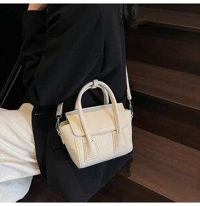 Model posing on stairs with beige lychee pattern leather tote bag in a casual business style