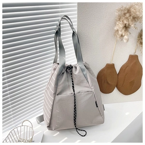 Detail of grey drawstring backpack featuring white side stripes and a front pocket