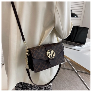 Détail d'un sac bandoulière café avec motif de lettres M et boucle métallique ronde