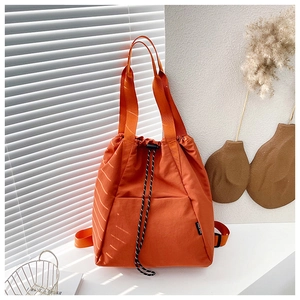 Detail view of orange canvas drawstring backpack with adjustable straps and front pocket
