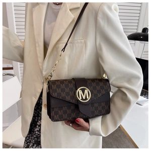 Détail du sac à main en cuir marron avec logo M doré et texture monogramme