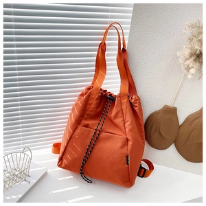Detail view of orange drawstring backpack with woven handles and front slip pocket detail