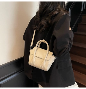 Close-up of beige litchi grain leather handbag with top handle and crossbody strap