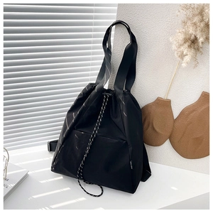 Detail of black drawstring backpack showing nylon texture and silver striped accents