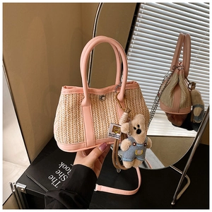 Detail of pink straw bag showing woven texture, leather handle and cute bear charm