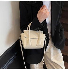 Close-up of beige pebble grain leather mini crossbody bag styled with a black suit jacket