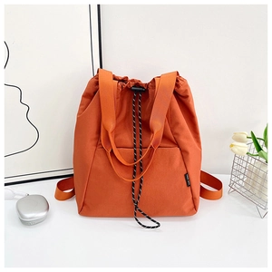 Detail of orange drawstring backpack showing textured fabric and stylish striped cords