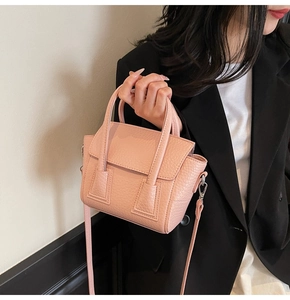 Detailed macro view of pink litchi grain leather handbag with round handles and flap cover