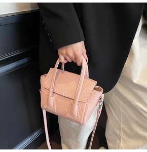 Detailed macro view of pink textured leather crossbody bag with elegant pebble finish