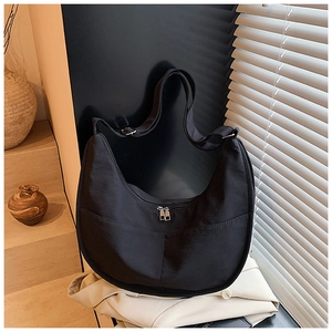 Detail of black crescent nylon tote bag showing metallic silver zippers and fabric texture