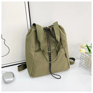 Detail of green drawstring tote bag featuring black and white cords and durable canvas texture