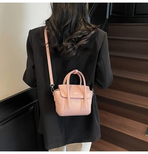 Rear view of model wearing pink pebbled leather mini crossbody bag on a dark staircase