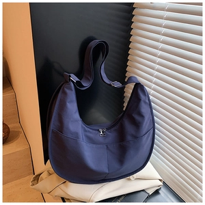 Detail of dark blue crescent canvas bag featuring adjustable strap and large front pockets