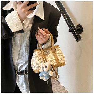 Detail of woven straw mini bag with brown leather trim and cute plush bear charm