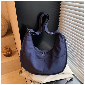 Detail view of navy blue half-moon canvas crossbody bag with adjustable wide strap and zip
