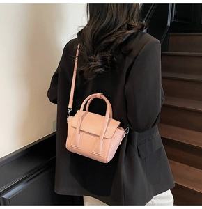 Pink textured small handbag shown with black blazer for size and style reference
