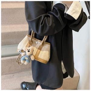 Detail of woven straw bag with leather trim and cute bear charm for summer beach