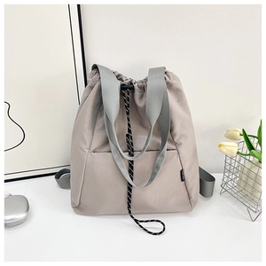 Modern grey drawstring backpack showing waterproof nylon fabric and woven handles in a lifestyle setting