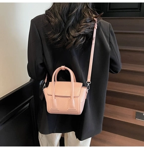 Pink pebble grain crossbody bag on model back view against indoor wooden stairs