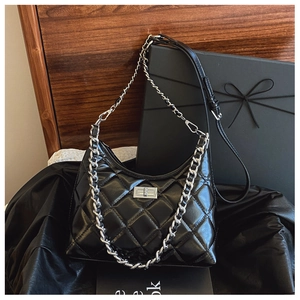 Détail du sac à main matelassé noir avec fermoir rotatif argenté et poignée chaîne