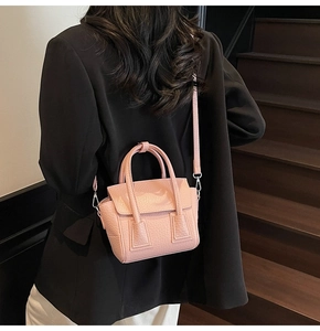 Detail of pink lychee grain leather handbag with silver hardware on a model outfit