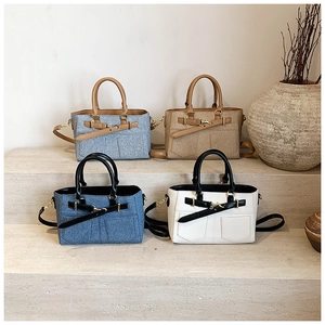 Detail view of stylish bucket bags in denim, canvas, and leather finishes on stone steps