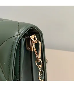 Détail de la boucle en D dorée et de la chaîne sur le sac matelassé vert foncé