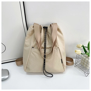 Close-up of a cream canvas backpack with brown wide straps and a black drawstring closure