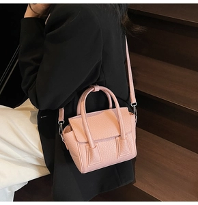 Macro detail of pink pebbled leather handbag with silver hardware on a staircase