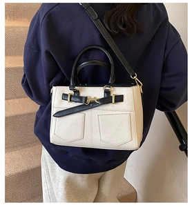 Close-up of oatmeal leather bucket bag featuring black straps and golden buckle details