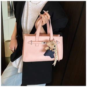 Detailed shot of pink pebble leather handbag with silver twist lock and bear charm