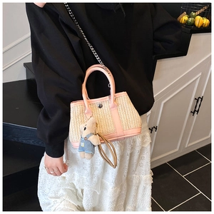Detail of pink woven straw tote bag with silver chain strap and cute bear charm