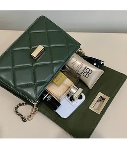 Détail de la sacoche matelassée vert foncé montrant l'intérieur spacieux et les accessoires