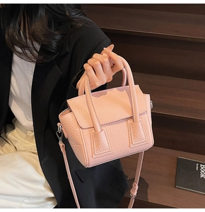 Close-up of pink litchi grain leather handbag with silver hardware and shoulder strap