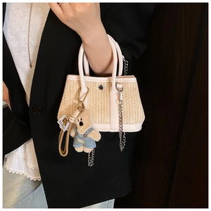Close-up of a summer woven straw beach bag with silver chain and cute teddy bear charm