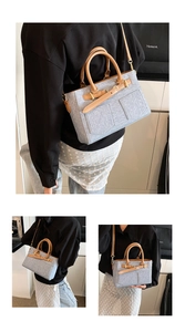 Detail of light blue denim handbag with brown leather handles and golden hardware accents