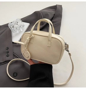 Detail of cream white pebbled leather mini Boston bag with smiley face charm and thin strap