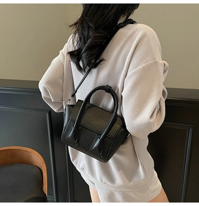 Close-up of black pebble leather mini tote bag with adjustable shoulder strap and handle