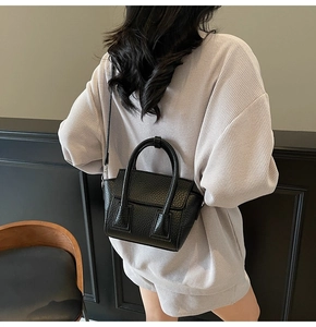 Close-up of black lychee grain leather handbag with crossbody strap on model