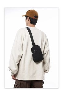 Minimalistische schwarze Nylon-Umhängetasche von hinten zur Darstellung der Größe am Modell